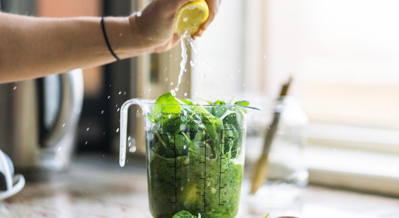 Frau macht frischen Pesto mit frisch gepresster Zitrone