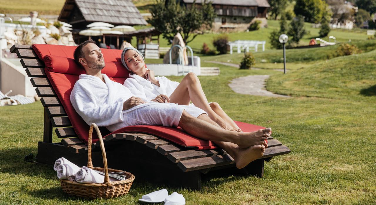 Paar entspannt auf Sonnenliegen im Wellnessgarten