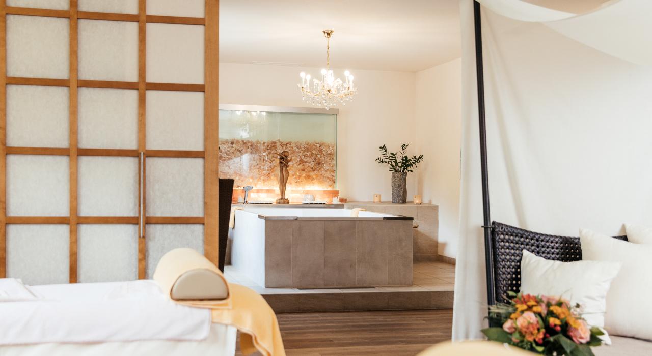 Ihr Day Spa in Kärnten - Ein Massagetisch, eine Badewanne in einem mit Blumen und Kerzen dekorierten Raum im 5-Sterne-Hotel in Bad Kleinkirchheim 
