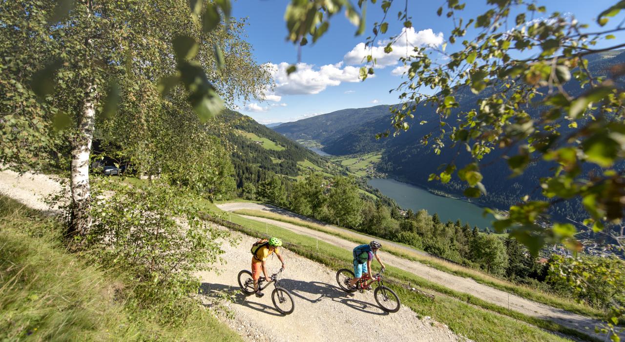 Zwei Personen beim Mountainbiken in Bad Kleinkirchheim genießen den Blick auf den See und die Natur