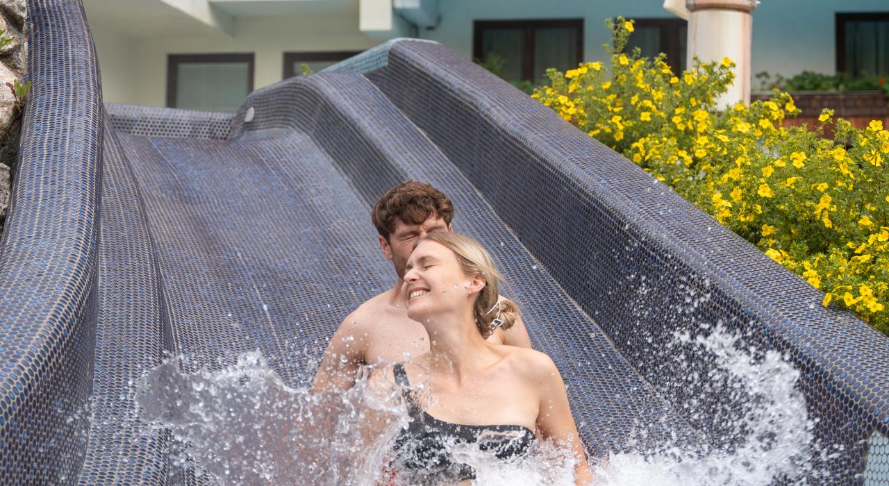 Zwei Personen auf der äußeren Poolrutsche in unserem Thermenhotel in Kärnten