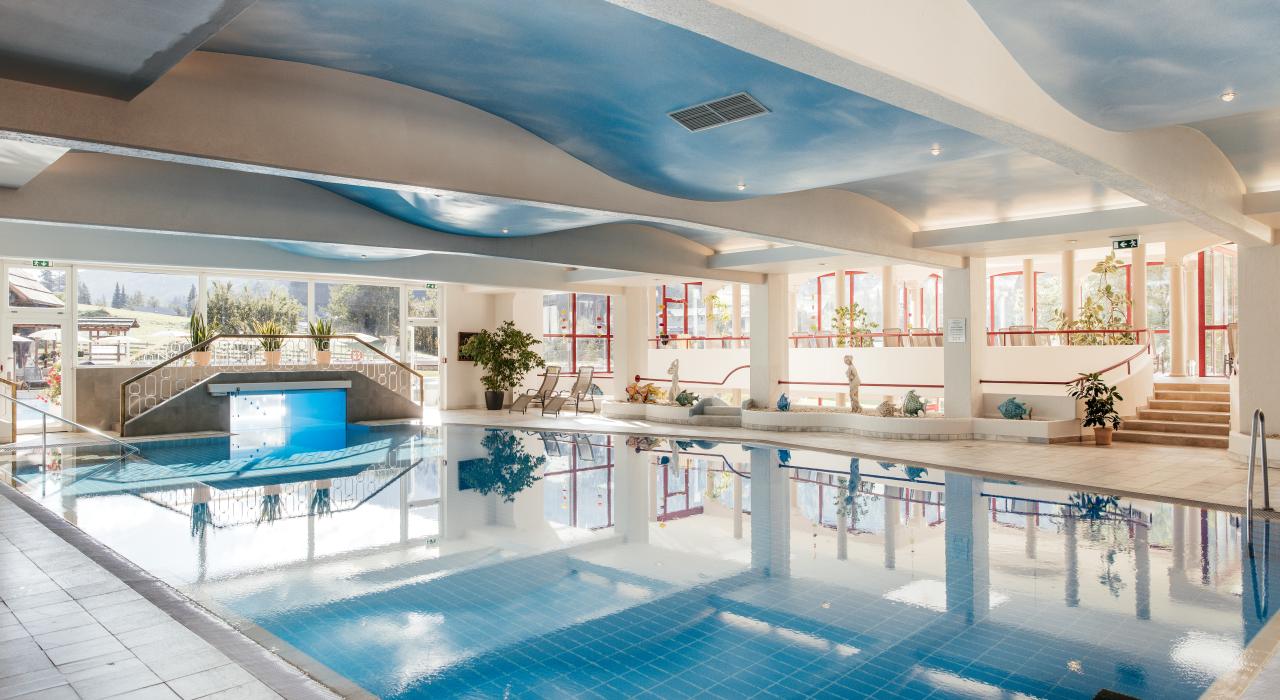 Der großzügige Innenpool mit großen Fenstern und Liegestühlen im 5-Sterne-Hotel in Bad Kleinkirchheim