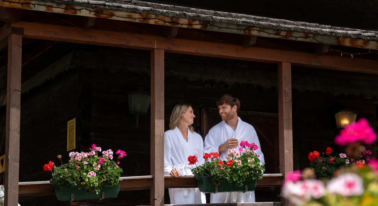 Ein Mann und eine Frau in Bademänteln unterhalten sich auf der Terrasse des 5-Sterne-Hotels in Bad Kleinkirchheim