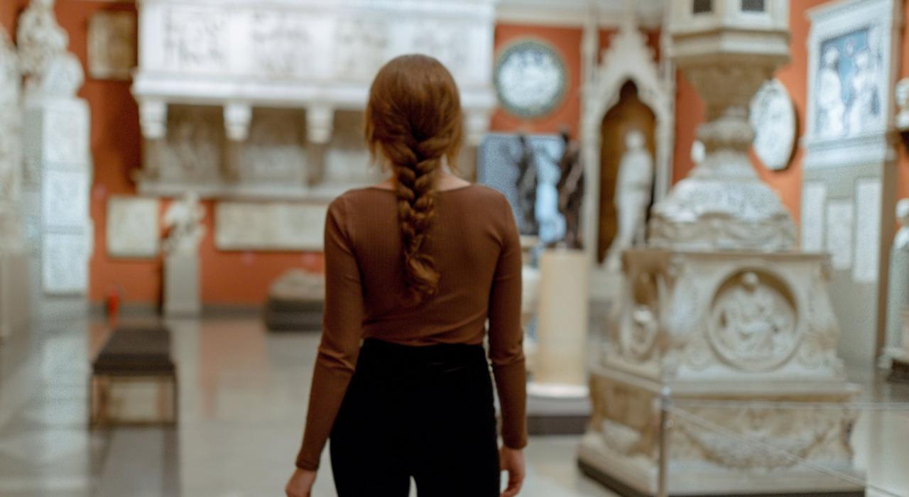Das Bild zeigt eine Person von hinten, die ein Museum oder eine Kunstgalerie besucht