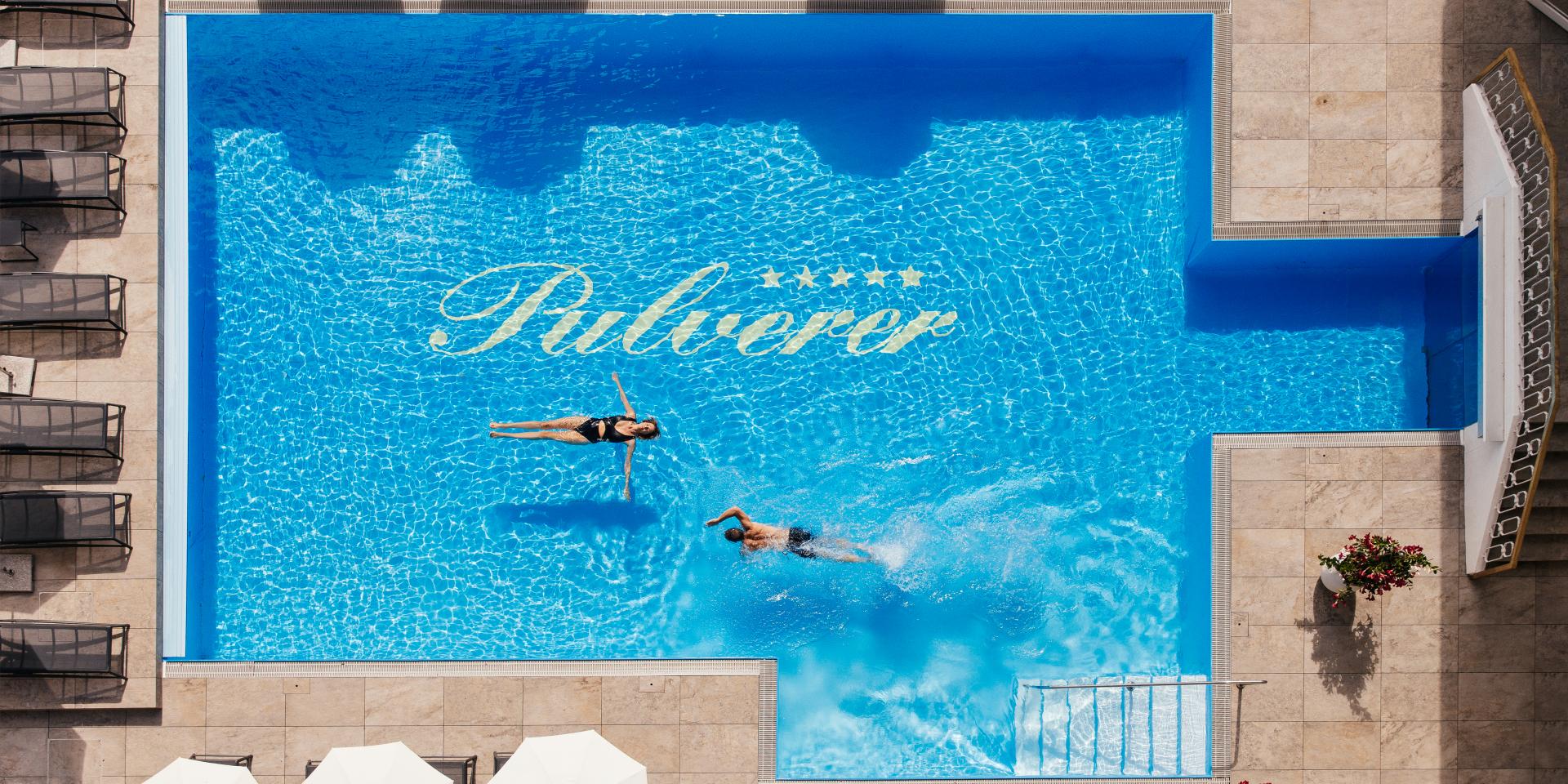 Foto aus der Luft von zwei Personen, die im Außenpool im Thermenhotel in Kärnten schwimmen