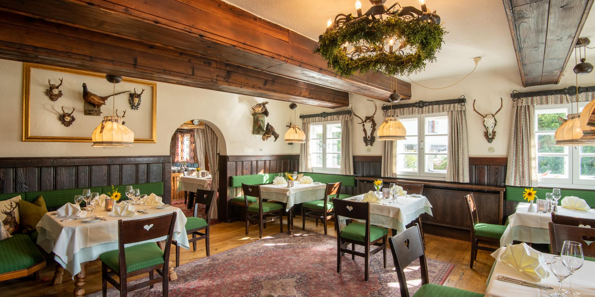 Der Blick auf das Restaurant Loystub'n, die Eventlocation in Kärnten, mit grünen Sitzmöbeln im Retrostil
