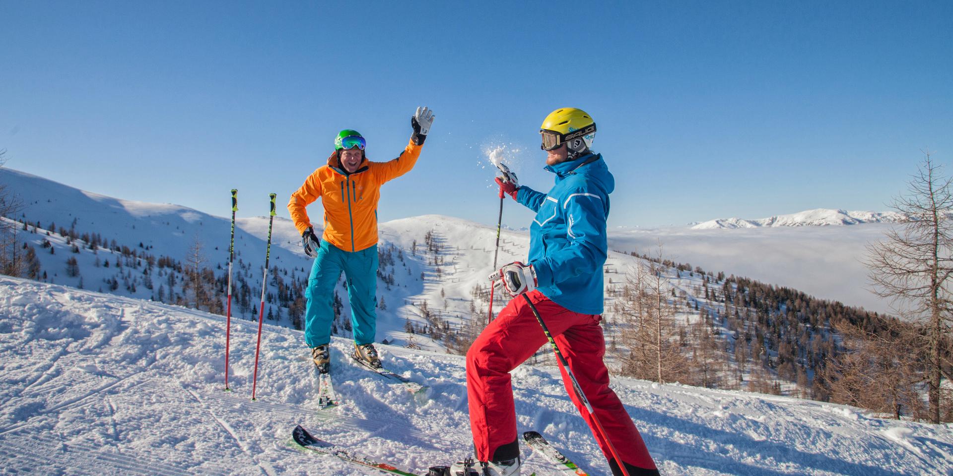 Ein Paar genießt einen sonnigen Tag beim Skifahren in Bad Kleinkirchheim. Mit farbenfroher Skibekleidung und perfekten Schneeverhältnissen erleben sie winterlichen Spaß pur.