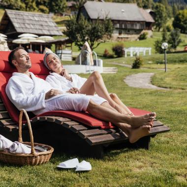 Paar entspannt auf Sonnenliegen im Wellnessgarten