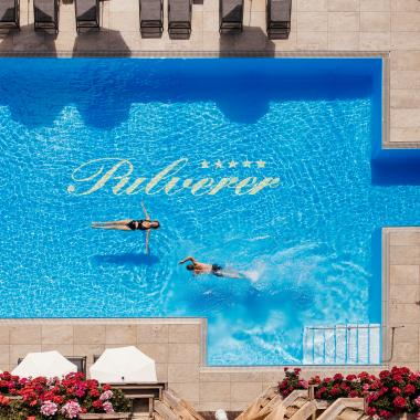 Ein Foto aus der Vogelperspektive von zwei Personen beim Schwimmen im Außenpool des 5 Sterne Hotels in Bad Kleinkirchheim.