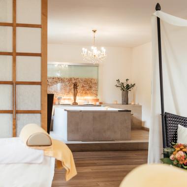 Ihr Day Spa in Kärnten - Ein Massagetisch, eine Badewanne in einem mit Blumen und Kerzen dekorierten Raum im 5-Sterne-Hotel in Bad Kleinkirchheim 
