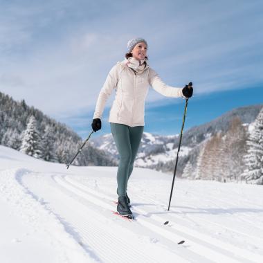 Eine Frau beim Langlaufen in den Bergen in ihrem Winterurlaub in Kärnten