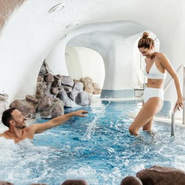 Ein Mann im Whirlpool und eine Frau beim Betreten des Whirlpools im 5-Sterne-Hotel in Bad Kleinkirchheim