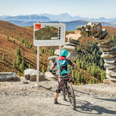 Ein Kind auf dem Fahrrad beim Lesen einer Karte mit Routen während des Urlaubs in unserem Familienhotel in Bad Kleinkirchheim