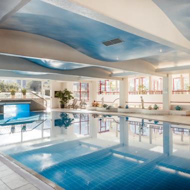 Der großzügige Innenpool mit großen Fenstern und Liegestühlen im 5-Sterne-Hotel in Bad Kleinkirchheim