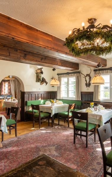 Der Blick auf das Restaurant Loystub'n, die Eventlocation in Kärnten, mit grünen Sitzmöbeln im Retrostil
