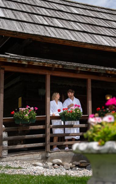 Ein Mann und eine Frau in Bademänteln unterhalten sich auf der Terrasse des 5-Sterne-Hotels in Bad Kleinkirchheim