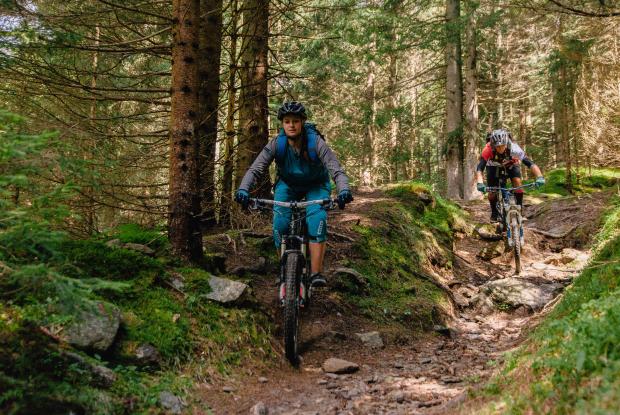 Frau und Mann fahren einen Trail im Wald auf einem Fahrrad