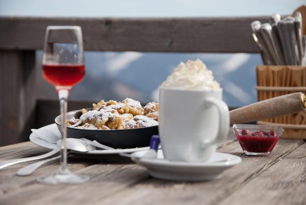 Eine Nahaufnahme einer Tasse mit Sahne, Kaiserschmarrn und Getränken auf dem Tisch im Winterurlaub in Kärnten