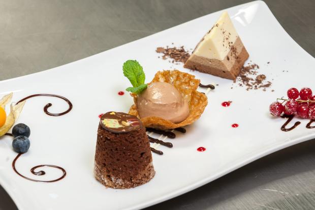 Nahaufnahme eines mit Schokolade und Früchten dekorierten Schokodesserts 