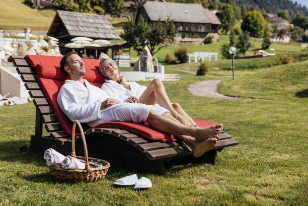 Paar entspannt auf Sonnenliegen im Wellnessgarten