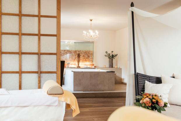 Ihr Day Spa in Kärnten - Ein Massagetisch, eine Badewanne in einem mit Blumen und Kerzen dekorierten Raum im 5-Sterne-Hotel in Bad Kleinkirchheim 
