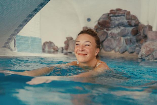 Frau entspannt im Innenpool des Hotels Pulverer