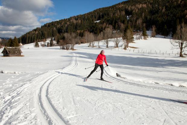 Eine Frau beim Langlaufen in ihrem Winterurlaub in Kärnten