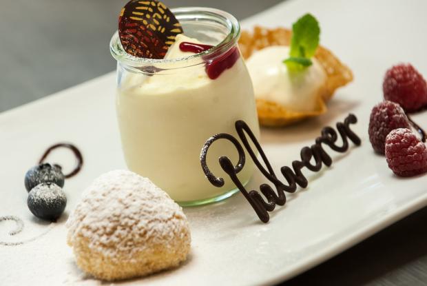 Nahaufnahme eines Desserts in einer Tasse mit Himbeeren und Pulverer in Schokoladenschrift in der Eventlocation in Kärnten