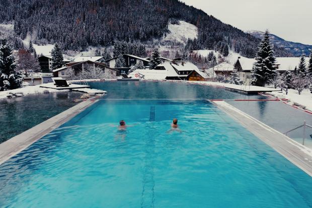 Gast im Infinitypool blickt auf Kärntner Bergwelt