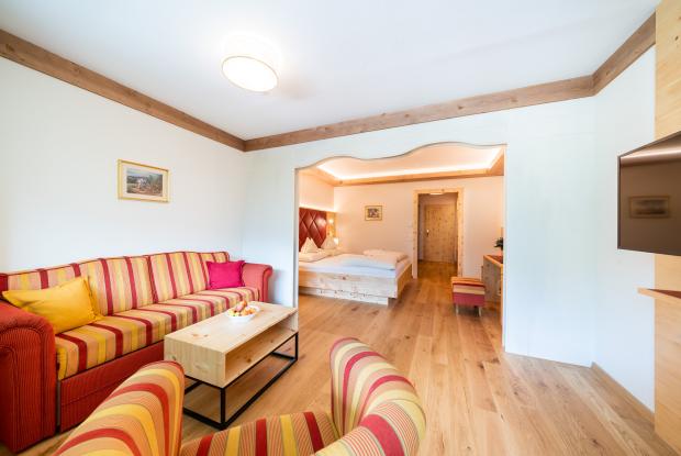 Ein Hotelzimmer mit Wohnzimmer, der mit einem rot-gelb gestreiften Sofa und Sesseln ausgestattet ist
