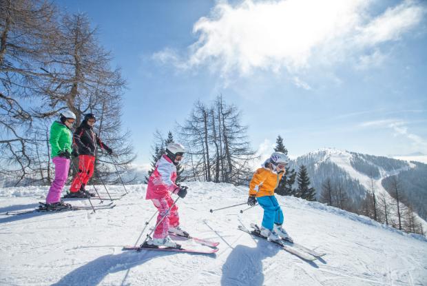 Eine Familie fährt in ihrem Winterurlaub in Kärnten Ski