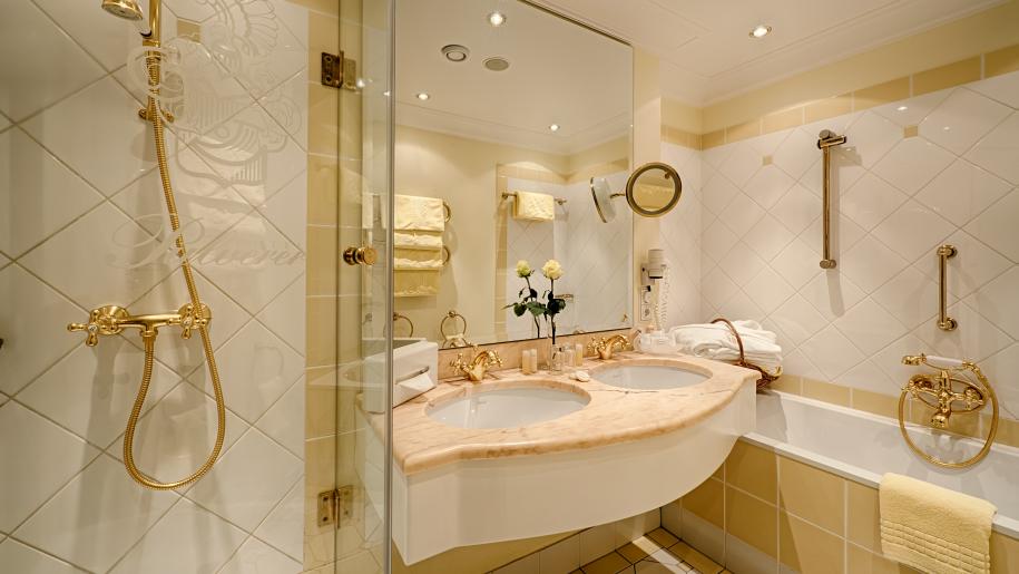 Ein luxuriöses Badezimmer mit zwei Waschbecken, goldenen Armaturen und einer Badewanne
